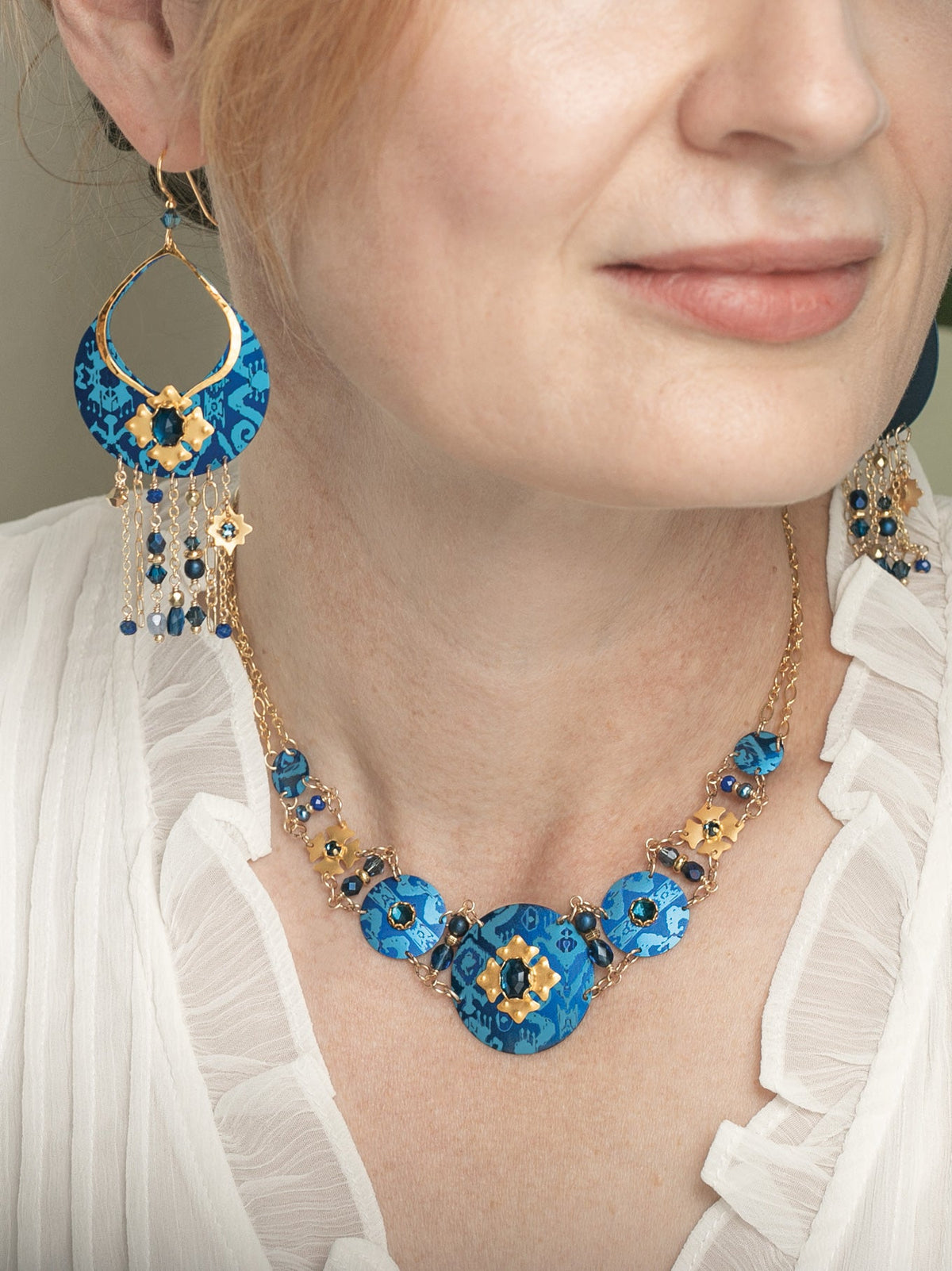 Model wearing the Holly Yashi 2026 Holiday Limited Edition Necklace and Earrings in sapphire blue and gold