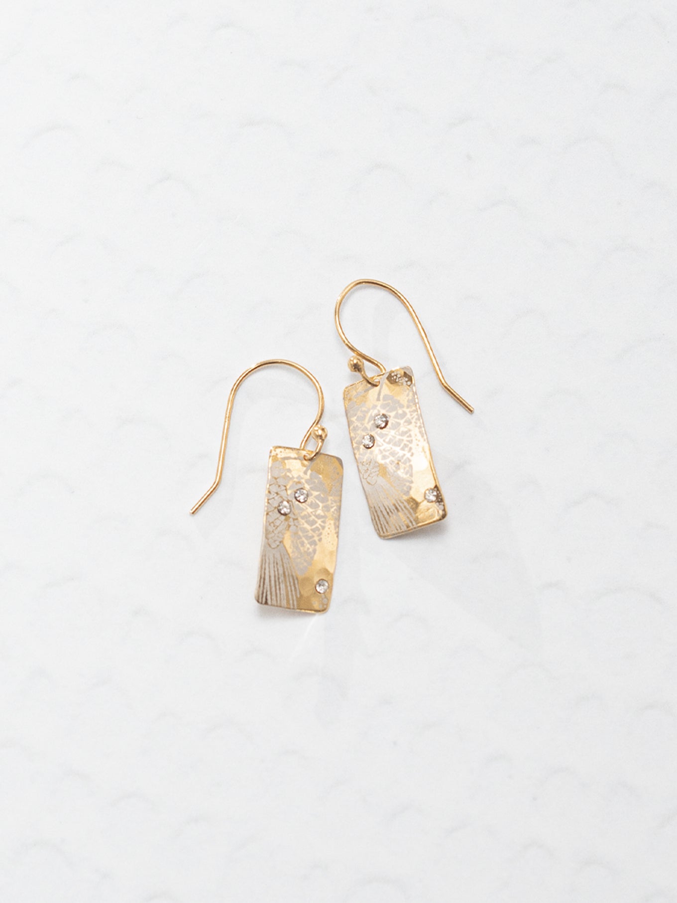 The Radiant Petra Earrings shine with precious metal and